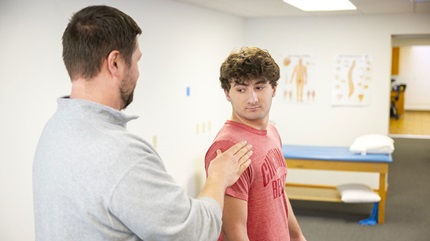 Charlie Johnson receiving a shoulder examination.