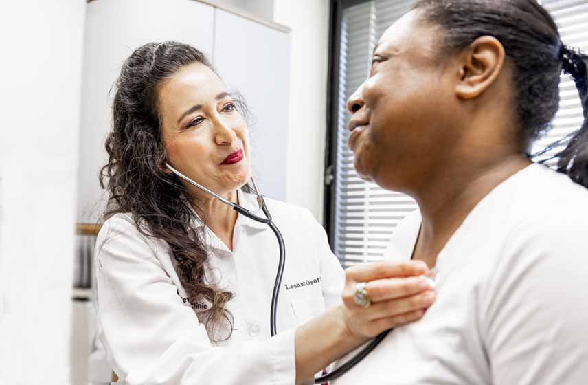 Doctor listens to patient's chest with stethoscope during a medical office exam.