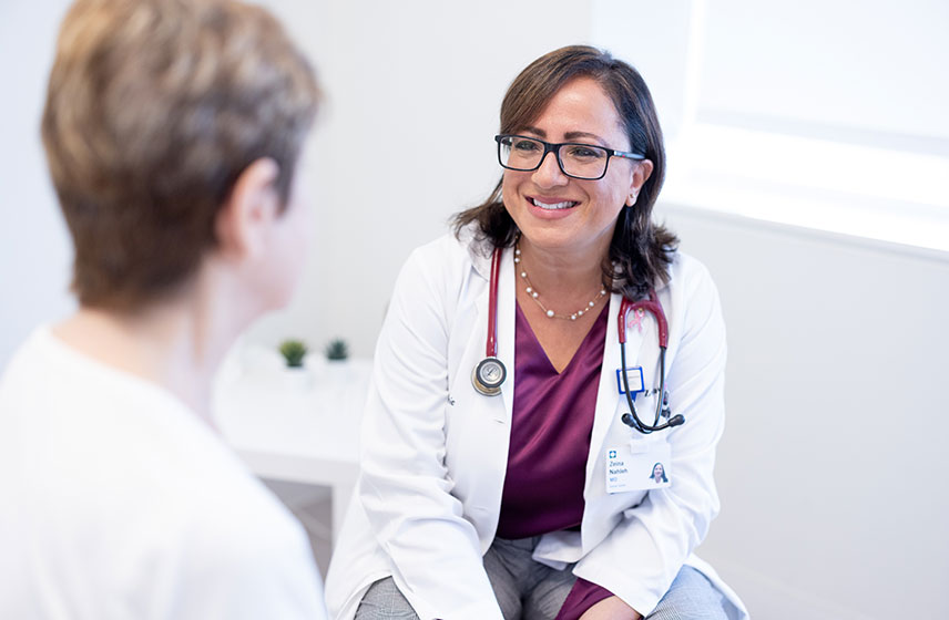Female doctor speaking with female patient in examination room.